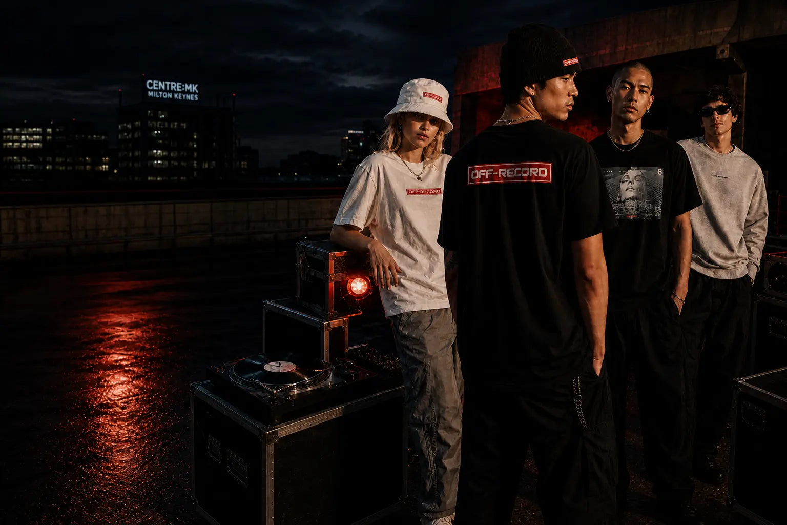 Four individuals standing on a rooftop at night with cityscape in the background | Off-Record