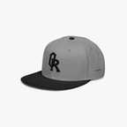 Grey and black snapback cap with a black embroidered 'OR' logo on the front, set against a plain light gray background.