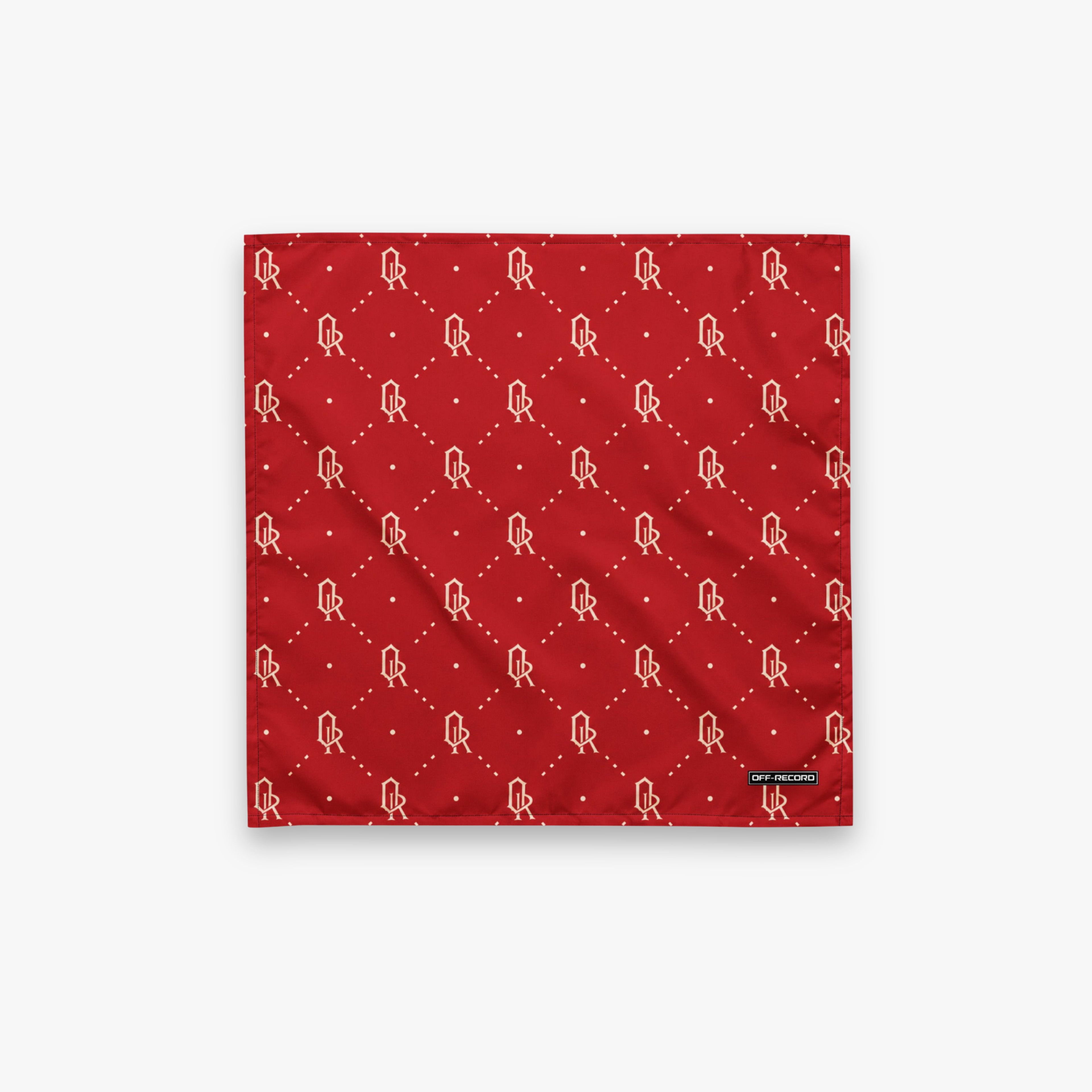 A square red bandana featuring a repeating white monogram pattern of 'OR' inside a diamond lattice, with a small black brand tag on the bottom right corner, displayed flat against a light gray background.